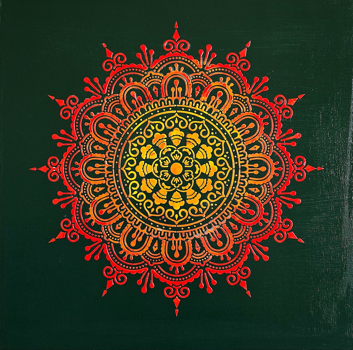 Decorative mandala with red and orange colors on a green background