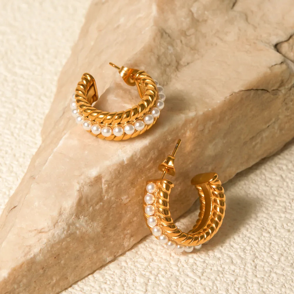 Gold stainless steel pearl C-hoop earrings, 18K gold-plated hypoallergenic jewelry displayed on stone background.