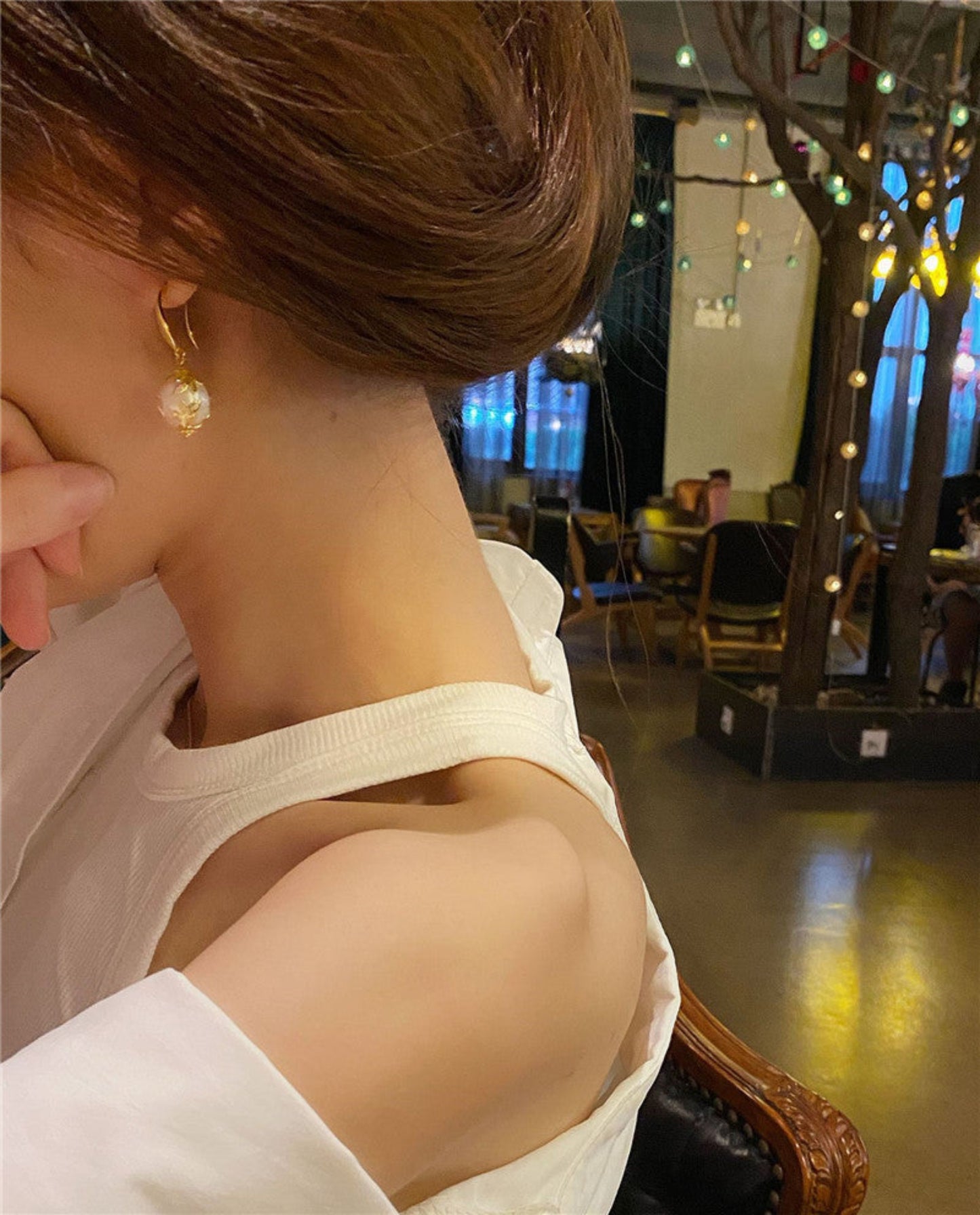 Close-up of a person wearing a gold earring in an indoor setting with blurred background