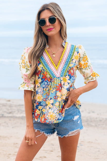 Woman in a colorful floral top and denim shorts on a beach.