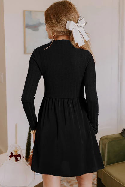 Back view of a woman wearing a black long-sleeve skater dress with a fitted bodice and flared skirt, styled with a white bow hair accessory, standing indoors near wall art and decor
