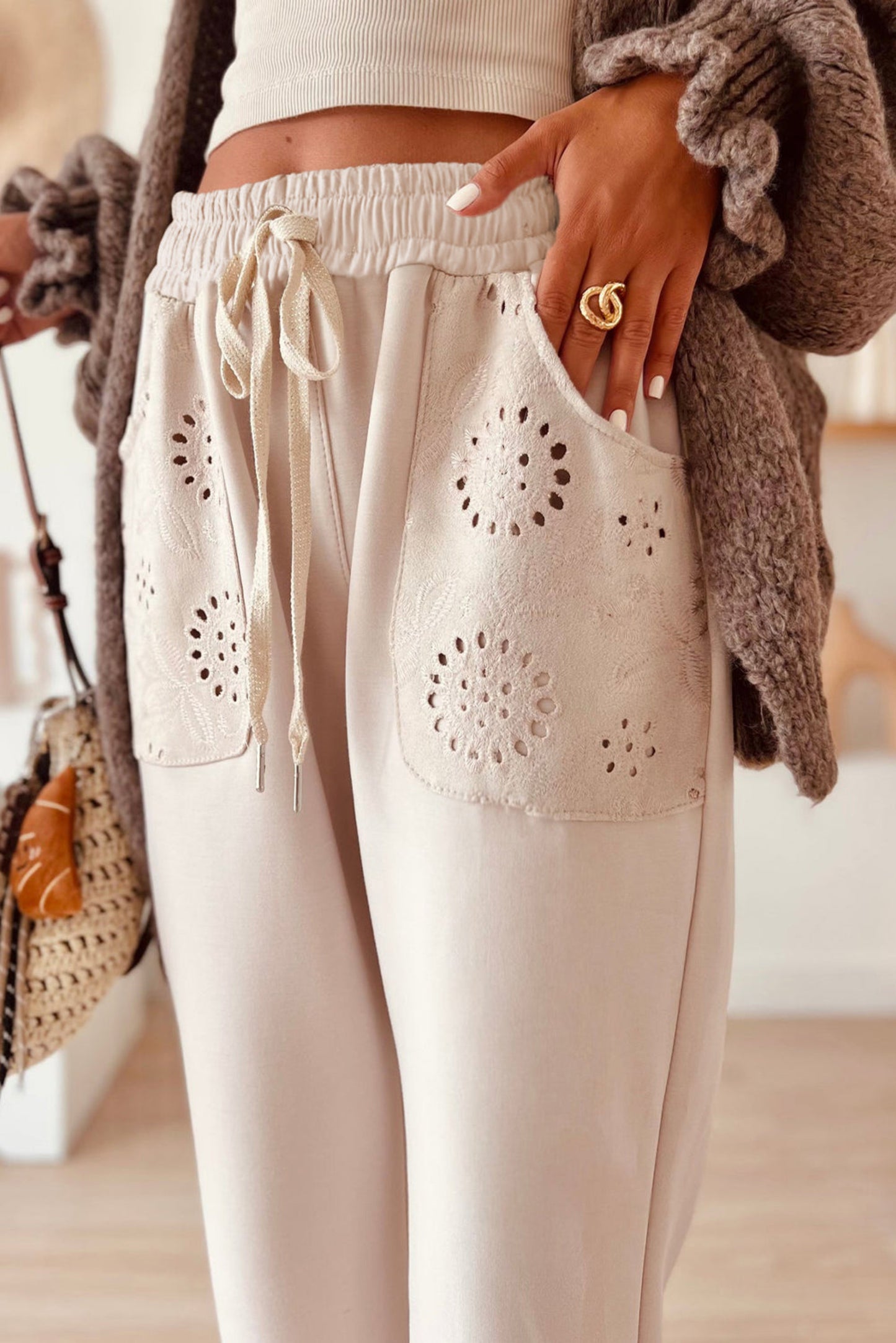 Beige pants with lace detailing worn by a person, with a blurred background.