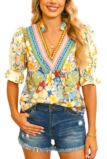 Woman wearing a colorful floral blouse and denim shorts against a neutral background