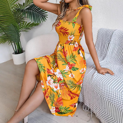Woman wearing a yellow floral dress sitting on a couch with a plant in the background