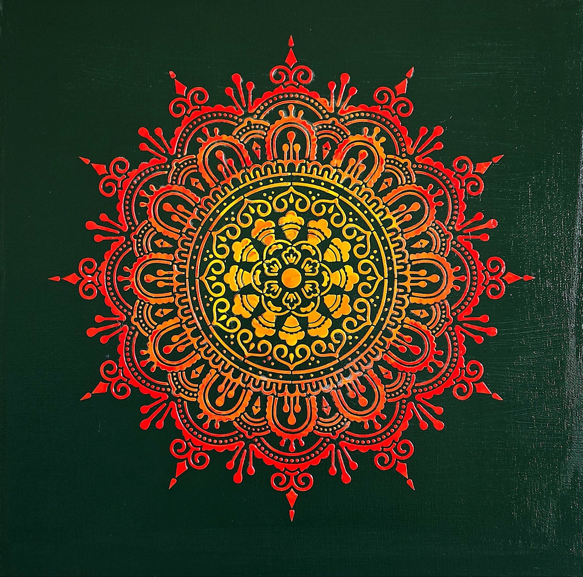 Decorative mandala with red and orange colors on a green background