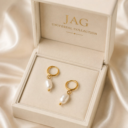 Gold earrings with pearls in a 'JAG Universal Collection' box on a beige fabric background